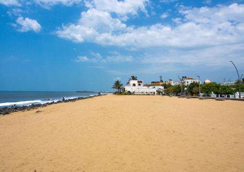 a sandy beach with houses and the ocean at La Maison Pondichéry in Puducherry