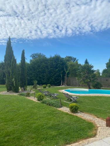 einen Pool in einem Garten mit Gras und Bäumen in der Unterkunft Gîte de la sablière in Courlay