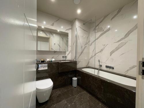 a bathroom with a tub and a toilet and a sink at luxurious, 2 bed, 2 bath penthouse apartment in highly desirable Chigwell CHCL F8 in Chigwell