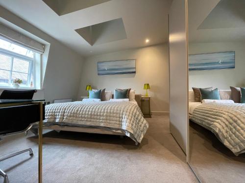 1 Schlafzimmer mit 2 Betten und einem Spiegel in der Unterkunft luxurious, 2 bed, 2 bath penthouse apartment in highly desirable Chigwell CHCL F8 in Chigwell