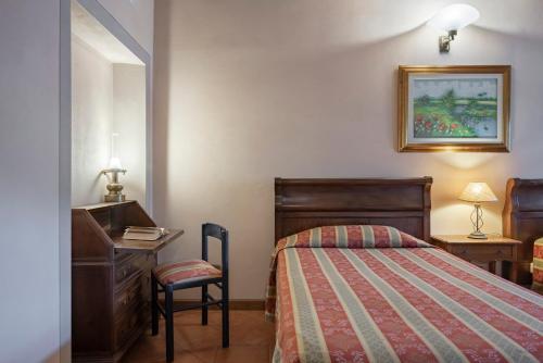 a bedroom with a bed and a desk and a chair at Villaggio Albergo San Lorenzo e Santa Caterina in Pescia