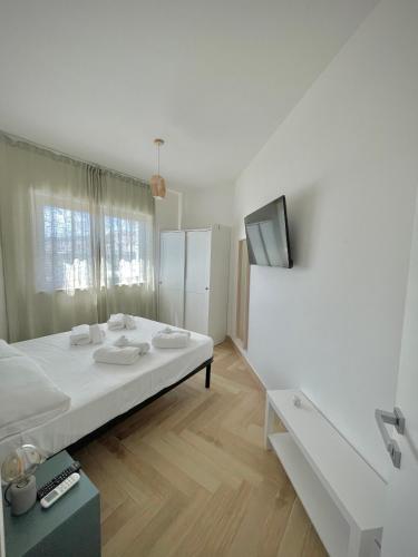 a white bedroom with a bed and a tv at Orti di Serapo -VERDE in Gaeta