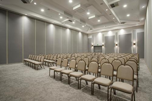 an empty room with a row of chairs and a screen at QOYA Hotel Curitiba, Curio Collection by Hilton in Curitiba