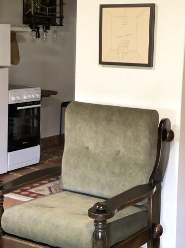 a green chair in a kitchen with a stove at Vikendice Stara Pruga in Gornji Milanovac