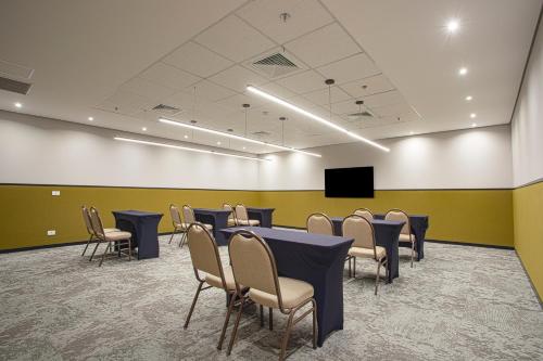 a conference room with tables and chairs and a tv at QOYA Hotel Curitiba, Curio Collection by Hilton in Curitiba