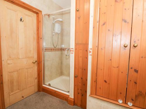 a bathroom with a shower and a glass door at Ash Farm Cottage in Holywell
