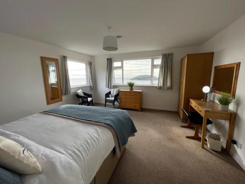 a bedroom with a bed and a desk and windows at Sea Spirit - Sweeping Sea Views first floor spacious modern apartment in Looe- with FREE parking! in Looe