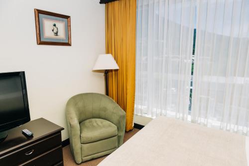 a hotel room with a chair and a television at Plaza Hotel and Suites in San Salvador