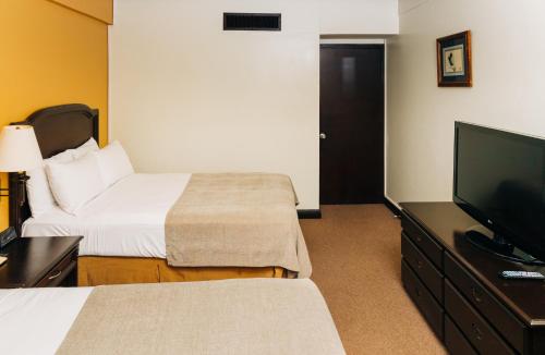 a hotel room with a bed and a flat screen tv at Plaza Hotel and Suites in San Salvador