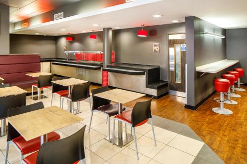 a restaurant with wooden tables and red chairs at ibis Nottingham Centre in Nottingham