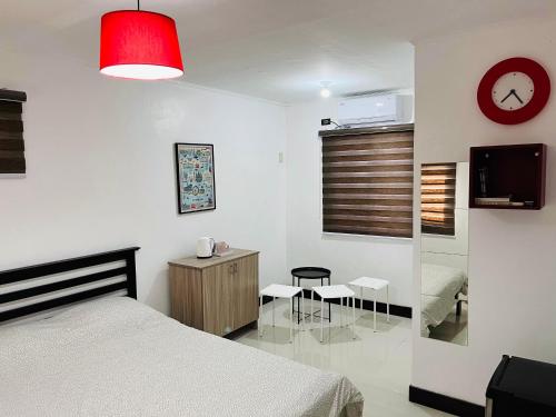 a bedroom with a bed and a desk and a clock at London Unit Tagaytay Wifi/Netflix/Parking in Tagaytay
