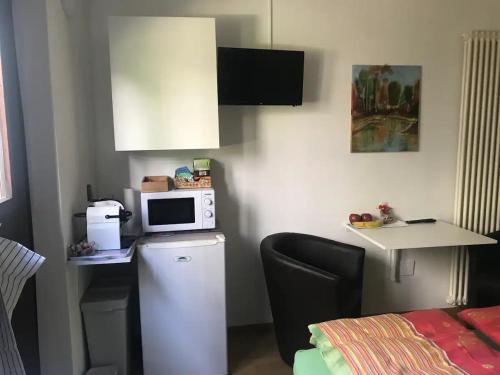 una pequeña cocina con microondas encima de una nevera en Locarno: camera indipendente in zona residenziale en Locarno