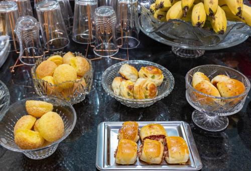 a table topped with bowls of pastries and bowls of bananas at Pousada Jardim Brasília in Brasilia