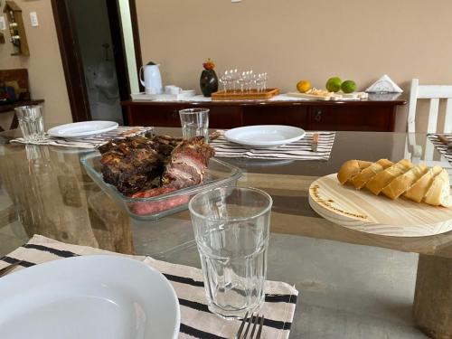 a glass table with a plate of meat and bread at Sitio do Marinho em Nova Trento in Nova Trento