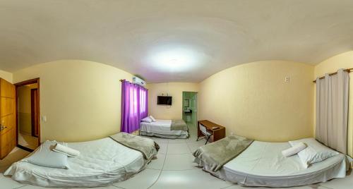 a room with two beds and a table in it at Pousada Jardim Brasília in Brasilia