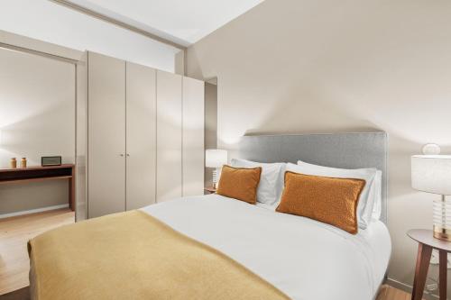 a bedroom with a large white bed with orange pillows at 108MM House in Porto