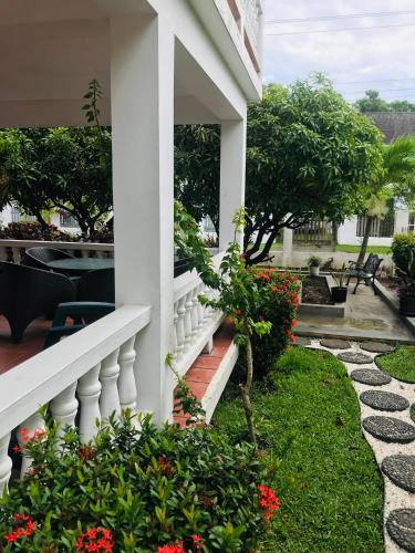 a white house with flowers on the porch at HCEAS villa is 5 min fr. airport & to the beaches in Bon Accord