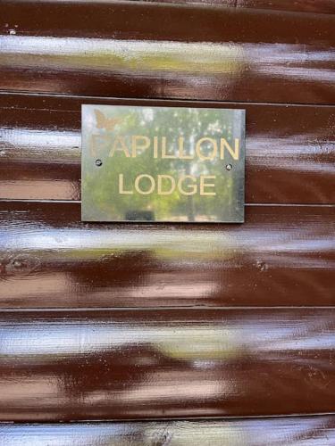 a sign that says amphibion lodge on a wooden wall at Cheerful 3-bedroom cabin with hot tub in King's Lynn