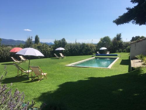 a yard with chairs and umbrellas and a swimming pool at La Grande Maison in Montmeyran