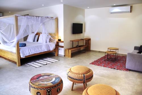 a bedroom with a bed and a tv and two stools at Au Paradis de Jeanne in Ngaparou