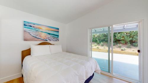 a white bedroom with a bed and a window at The Heathercliff in Malibu