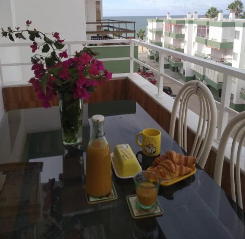 una mesa con zumo de naranja y cruasanes en el balcón en Frente al mar, en Rota