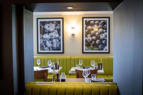 a dining room with two tables and a yellow couch at Best Western Gables Hotel in Falfield