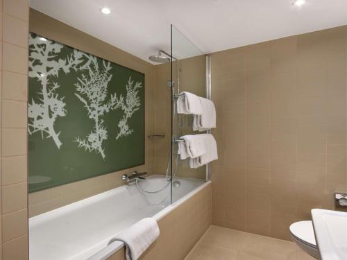 a bathroom with a shower and a tub and a sink at Radisson Blu Hotel, Hasselt in Hasselt