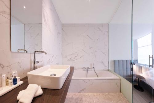 Radisson Blu Hotel, Hasselt في هاسيلت: حمام أبيض مع حوض ومغسلة