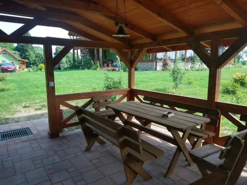 einen Picknicktisch aus Holz und zwei Bänke auf einer Terrasse in der Unterkunft Zielona Chatka pod Srebrnym Żurawiem in Wydminy