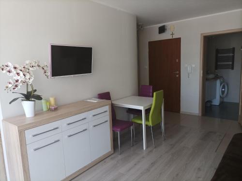 a kitchen with a table and chairs and a tv on the wall at Apartament Zielona Wydma in Łeba