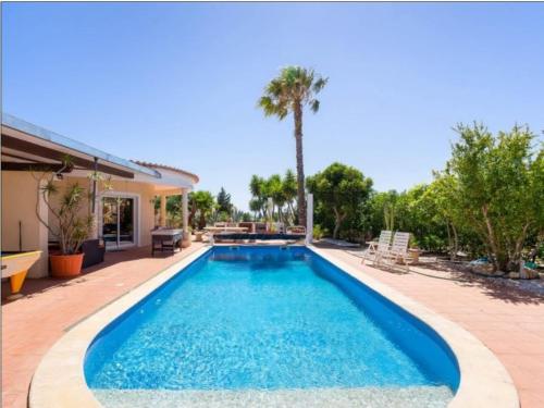 a swimming pool in front of a house at Oceanfront Villa - 8 rooms, 2 kitchens with pool, billiard table and Beach-Volleyball Court in Carvoeiro