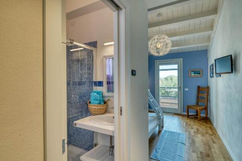 une salle de bain bleue avec un lavabo et une douche dans l'établissement La Casa degli Ulivi appartamento in villa con patio, à Quartu SantʼElena