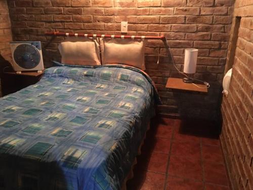 ein Schlafzimmer mit einem Bett und einer Ziegelwand in der Unterkunft Hermosa cabaña con vista a la montaña in Tunuyán