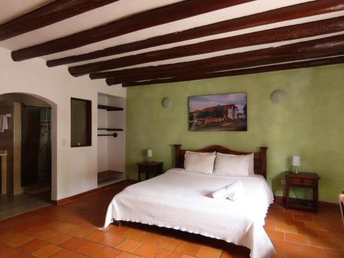 a bedroom with a white bed and a green wall at HOTEL AQUA VITAE in Villa de Leyva