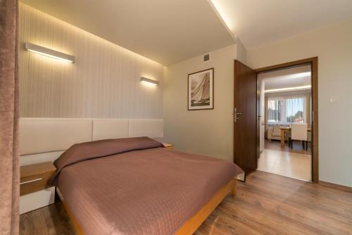 a bedroom with a large bed and a dining room at Apartament Marina in Jastarnia