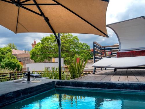 an umbrella and a chair next to a swimming pool at Casa No Name Small Luxury Hotel in San Miguel de Allende