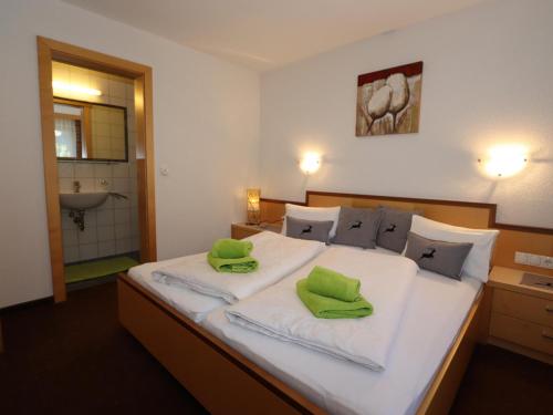 ein Schlafzimmer mit einem großen weißen Bett mit grünen Kissen in der Unterkunft Apart Altavista in Kappl