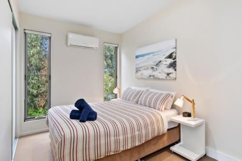 a white bedroom with a bed and two windows at OG- By the Sea, 400m to Beach in Ocean Grove