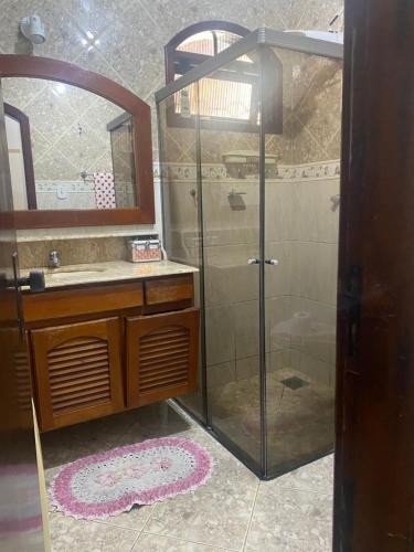 uma casa de banho com um chuveiro, um lavatório e um espelho. em Casa com piscina cabo frio em Cabo Frio
