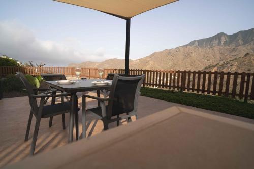a table with chairs and an umbrella on a patio at BASÂLTO Casas Rurales in Hermigua