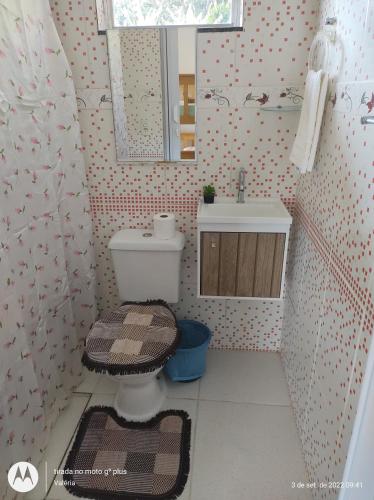 a bathroom with a toilet and a sink and a mirror at Suítes Carla e Carol in Praia de Araçatiba
