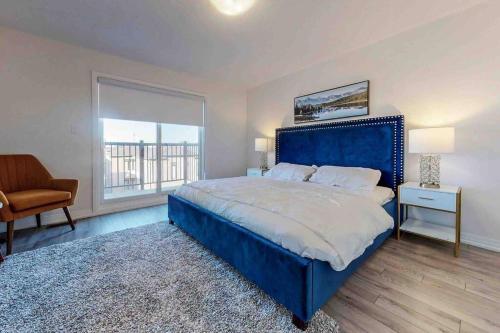 um quarto com uma grande cama azul e uma janela em NEWLY BUILT LUXURIOUS 3BRM TOWN HS/AIRPORT/PARKING em Brampton