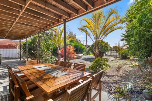 - patio z drewnianym stołem i krzesłami w obiekcie Little Boat Beach House at Aldinga Beach by Wine Coast Holiday Rentals w mieście Aldinga Beach