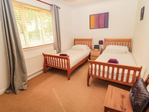 2 Betten in einem Zimmer mit Fenster in der Unterkunft Millennium Cottage in Alnwick