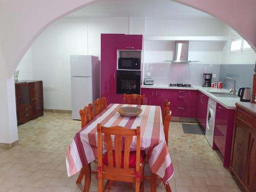 kuchnia ze stołem, krzesłami i fioletowymi szafkami w obiekcie LES 4L Caïmite w mieście Le Carbet