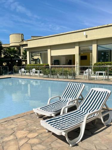 two lounge chairs sitting next to a swimming pool at Aldeia das Águas Park Resort - Flat B309 Quartier in Barra do Piraí