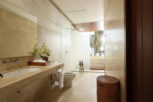 a bathroom with a toilet and a sink and a mirror at Amarta Beach Retreat by Nakula in Tabanan