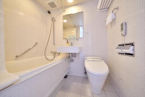 a white bathroom with a toilet and a sink at Senagajima Island Resort & Spa in Tomigusuku
