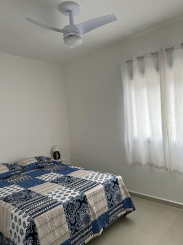 a bedroom with a bed with a ceiling fan at Apartamento pé na areia in Itanhaém